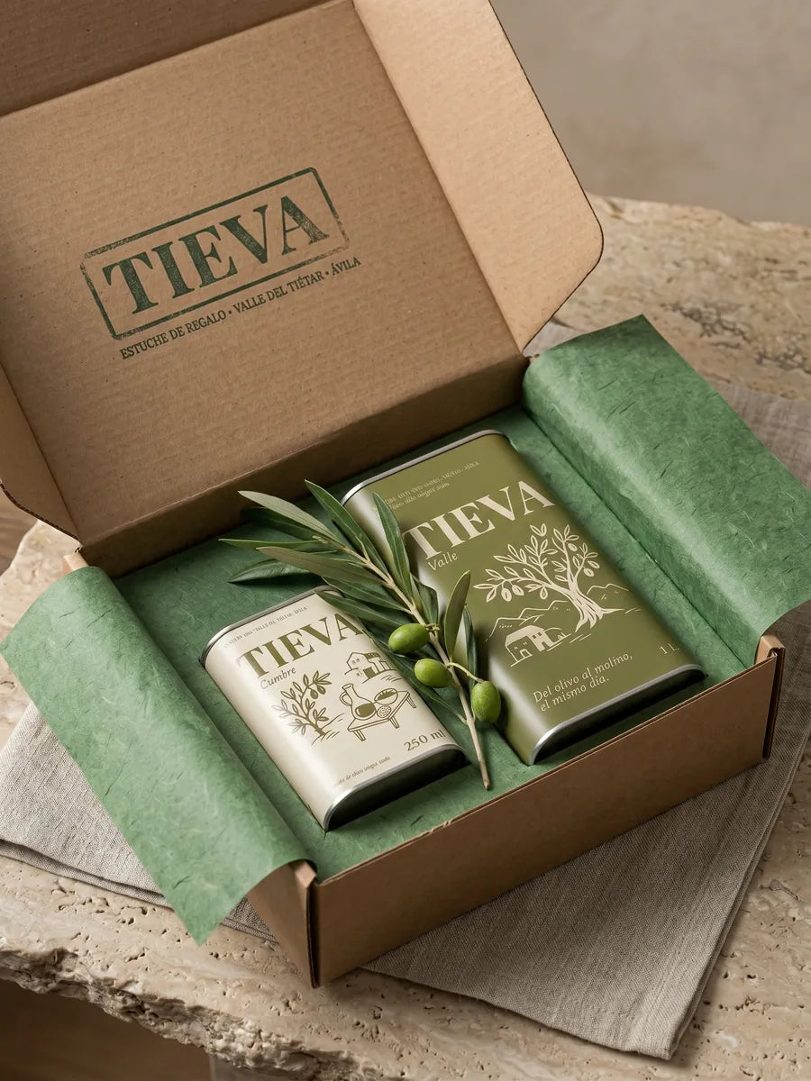 La caja de Tieva abierta, con una lata Valle de un litro y una Cumbre de 250 ml sobre papel de seda verde