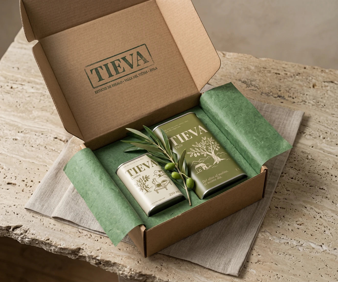 La caja de Tieva abierta, con una lata Valle y una Cumbre sobre papel de seda verde